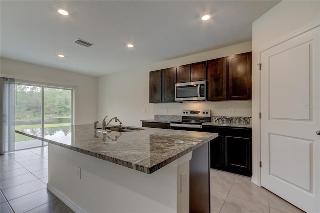 33351 Apricot Tree Ct, Wesley Chapel, FL 33543 - kitchen featuring stainless steel appliances, light tile patterned floors, dark brown cabinetry, dark stone countertops, and recessed lighting