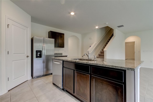 33351 Apricot Tree Ct, Wesley Chapel, FL 33543 - kitchen featuring stainless steel appliances, arched walkways, light stone countertops, a kitchen island with sink, and recessed lighting