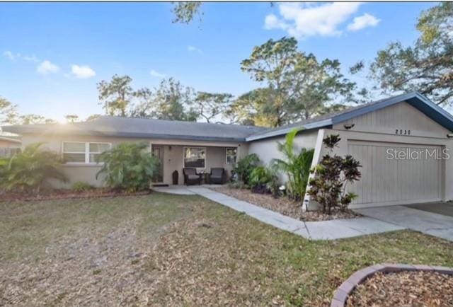 ranch-style home featuring a garage and a front lawn