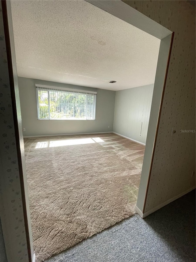 carpeted empty room with a textured ceiling