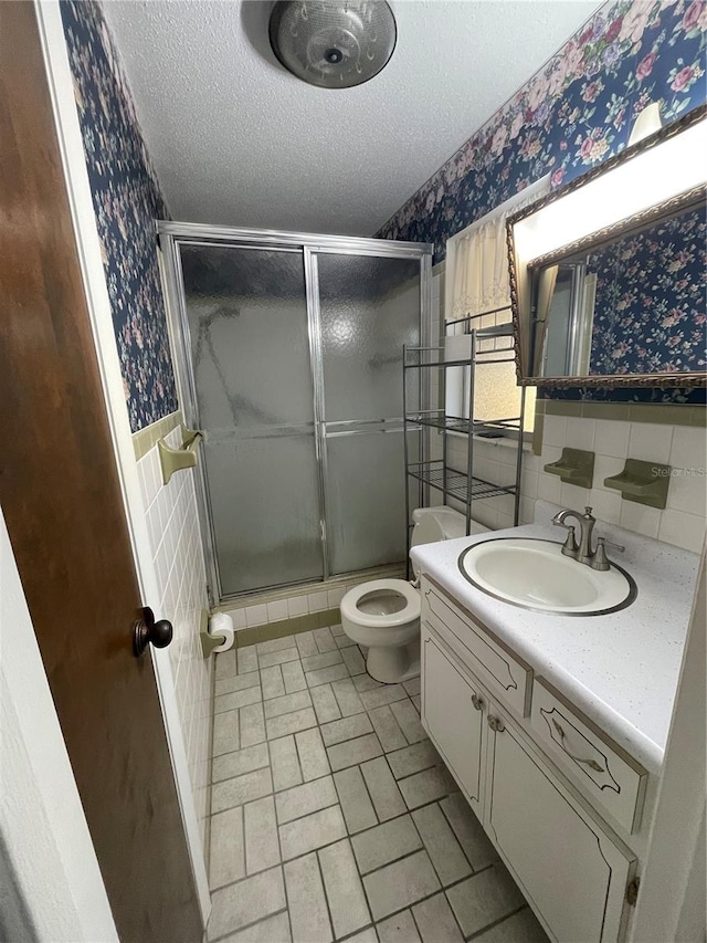 bathroom featuring toilet, tile walls, a textured ceiling, an enclosed shower, and vanity