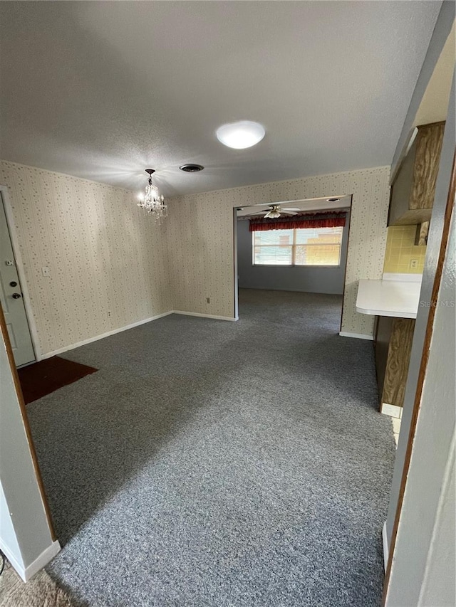 unfurnished room with dark carpet and a notable chandelier