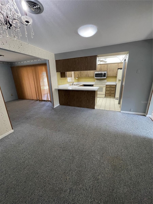 kitchen featuring light carpet, kitchen peninsula, a textured ceiling, and white appliances