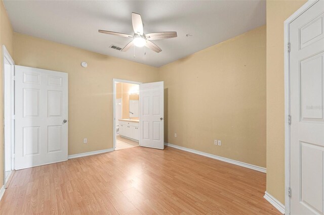 unfurnished bedroom with light wood-type flooring, ceiling fan, and ensuite bath