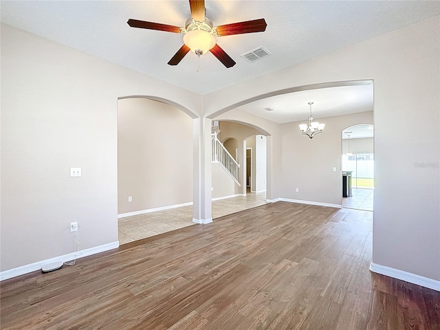 empty room featuring light wood-type flooring, a textured ceiling, and ceiling fan with notable chandelier