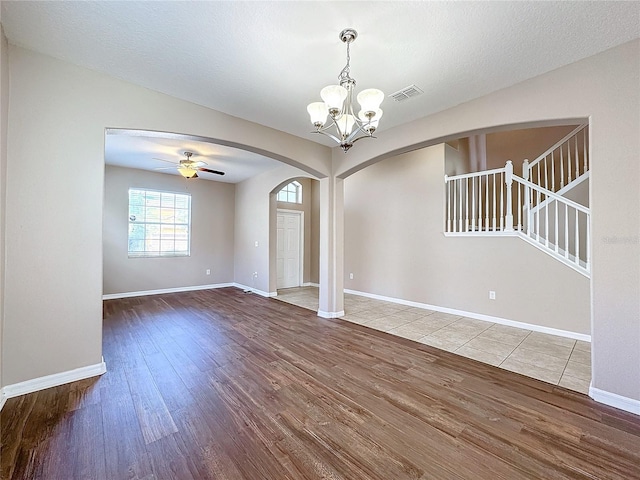 spare room with hardwood / wood-style flooring, ceiling fan with notable chandelier, and a textured ceiling