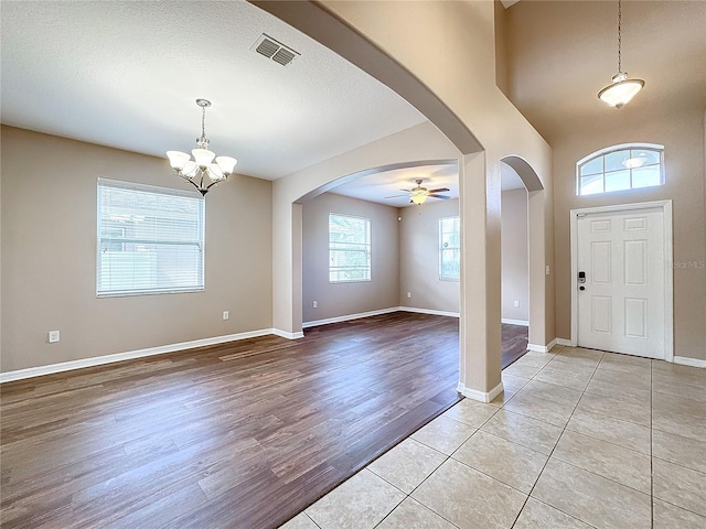 entryway featuring light wood-type flooring, ceiling fan with notable chandelier, and a textured ceiling