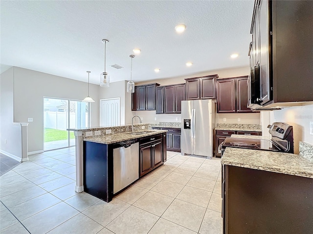 kitchen featuring stainless steel appliances, dark brown cabinetry, sink, light tile patterned floors, and pendant lighting