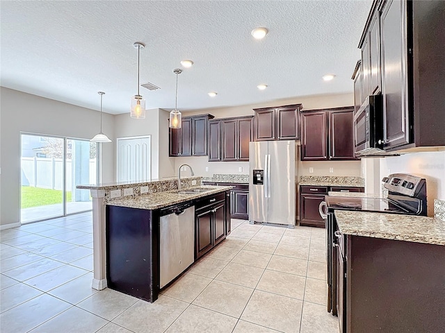 kitchen featuring stainless steel appliances, dark brown cabinets, light tile patterned floors, pendant lighting, and sink