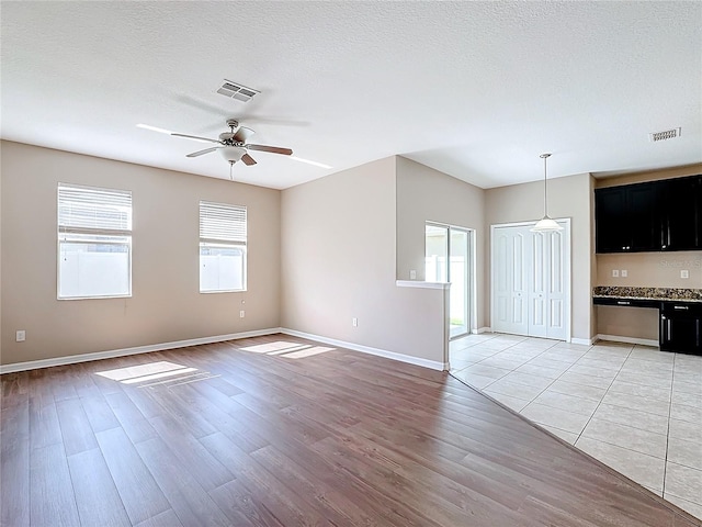 empty room with light hardwood / wood-style floors, ceiling fan, and a textured ceiling