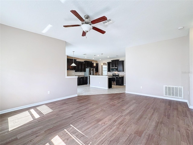 unfurnished living room with hardwood / wood-style floors, ceiling fan, and a textured ceiling