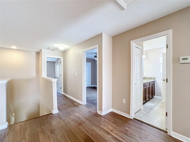 hall with a textured ceiling and light hardwood / wood-style flooring