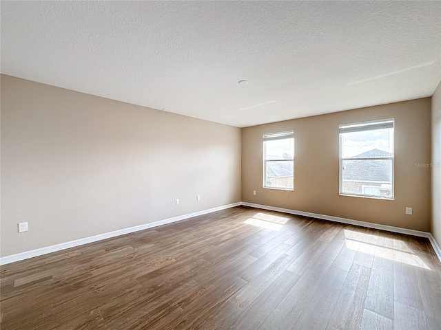 unfurnished room with hardwood / wood-style flooring and a textured ceiling