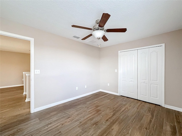 unfurnished bedroom with dark hardwood / wood-style flooring, a closet, a textured ceiling, and ceiling fan