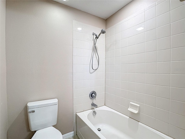 bathroom featuring tiled shower / bath combo and toilet