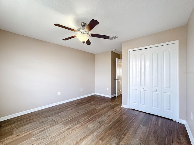 unfurnished bedroom featuring dark wood-type flooring, ceiling fan, a textured ceiling, and a closet