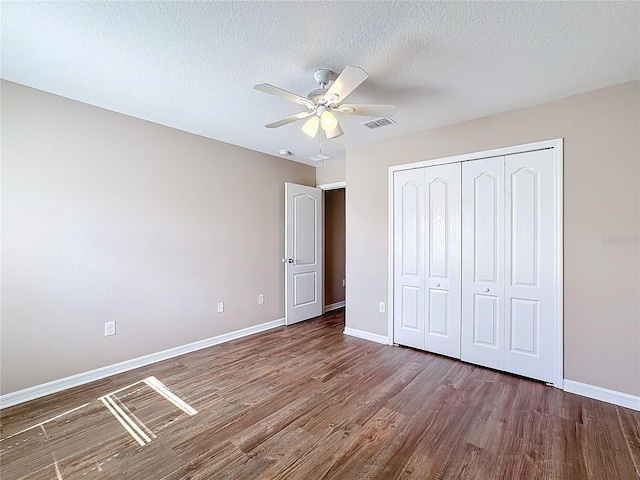 unfurnished bedroom featuring hardwood / wood-style floors, ceiling fan, a textured ceiling, and a closet