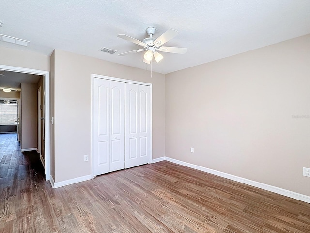 unfurnished bedroom featuring hardwood / wood-style floors, ceiling fan, a textured ceiling, and a closet