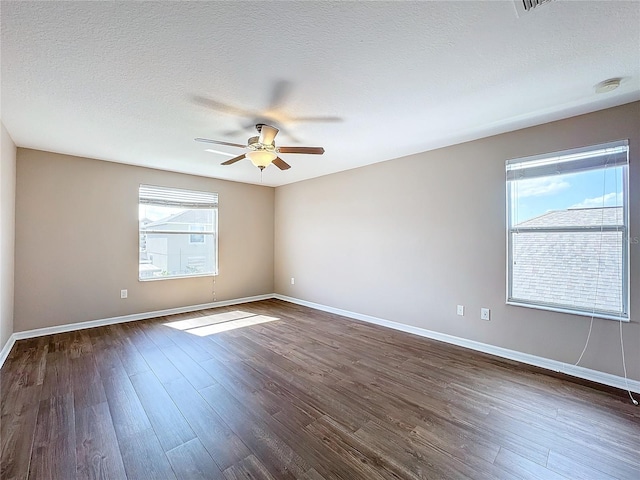 empty room featuring dark hardwood / wood-style flooring, ceiling fan, a textured ceiling, and a healthy amount of sunlight