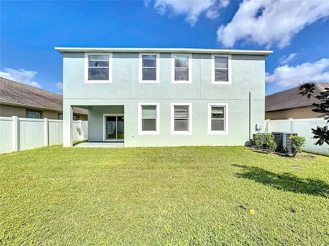 rear view of house with a lawn and central AC