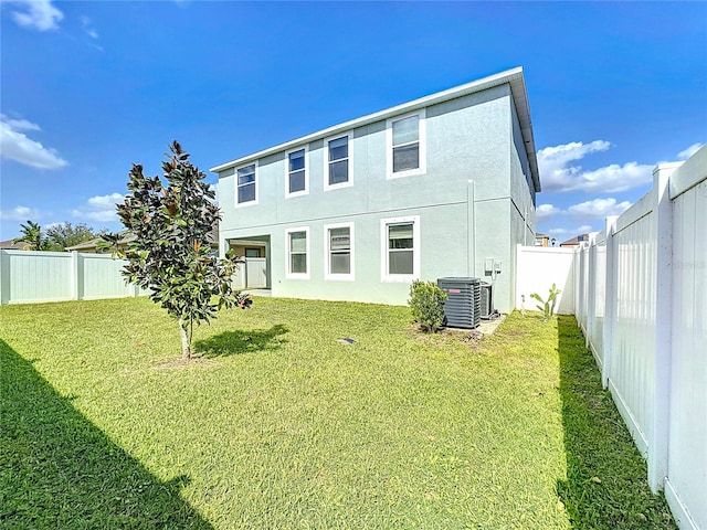 rear view of property with central air condition unit and a yard