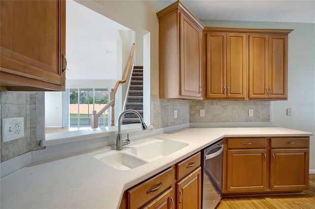 kitchen with stainless steel dishwasher, light hardwood / wood-style flooring, sink, and decorative backsplash