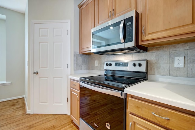 kitchen with tasteful backsplash, appliances with stainless steel finishes, and light hardwood / wood-style floors