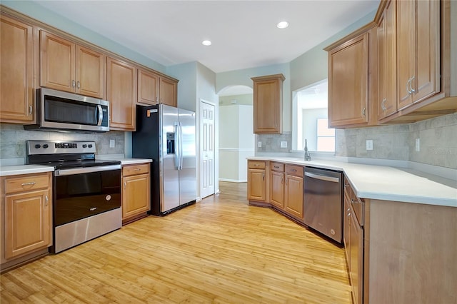 kitchen featuring stainless steel appliances, light hardwood / wood-style floors, and tasteful backsplash