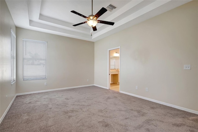 carpeted spare room featuring ceiling fan and a tray ceiling