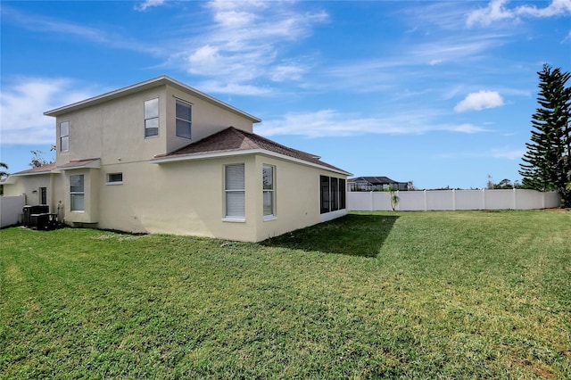 back of house featuring central AC unit and a lawn