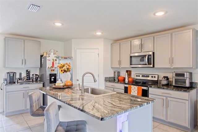 kitchen featuring appliances with stainless steel finishes, sink, an island with sink, and light tile patterned flooring