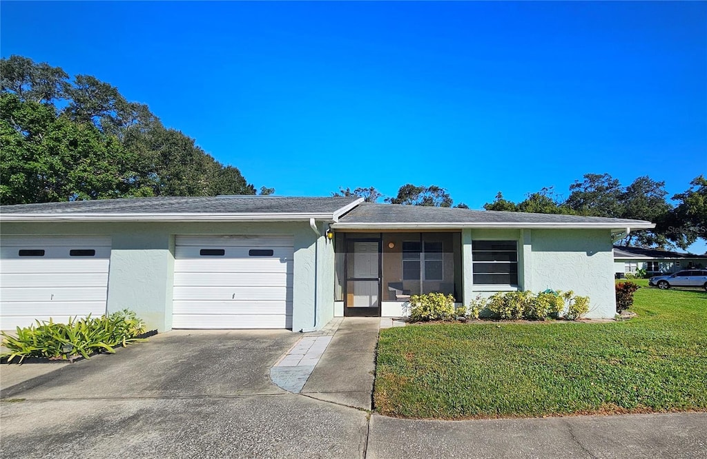 view of front facade with concrete driveway, a front lawn, an attached garage, and stucco siding