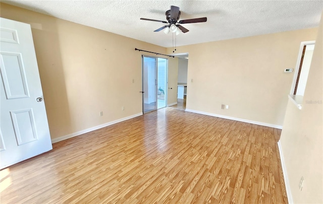 unfurnished room featuring a textured ceiling, light wood-type flooring, a ceiling fan, and baseboards