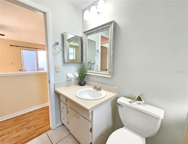 half bath featuring tile patterned flooring, baseboards, vanity, and toilet