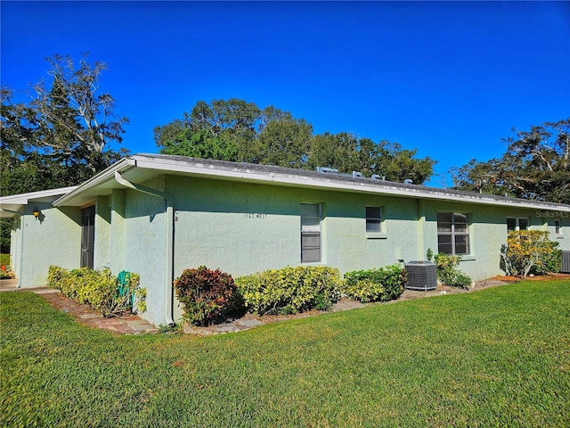 view of property exterior featuring central air condition unit, a lawn, and stucco siding