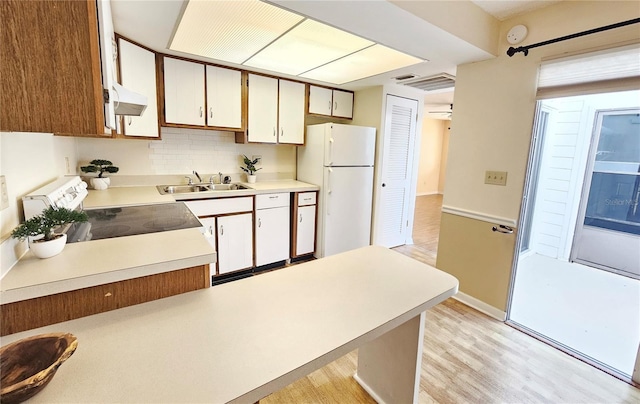 kitchen with white cabinets, stove, freestanding refrigerator, light countertops, and a sink