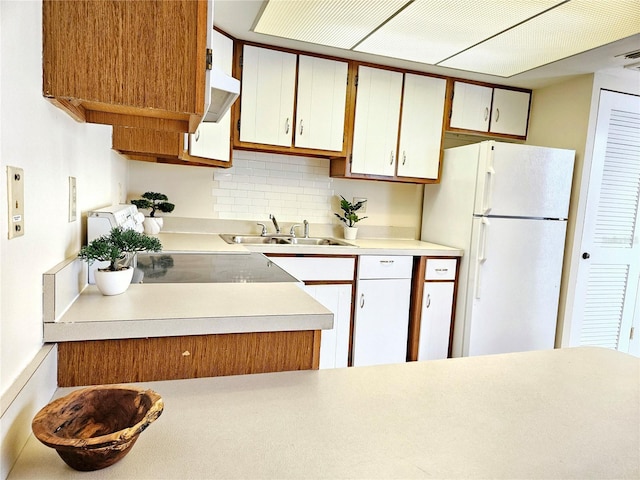 kitchen with freestanding refrigerator, white cabinets, light countertops, and a sink