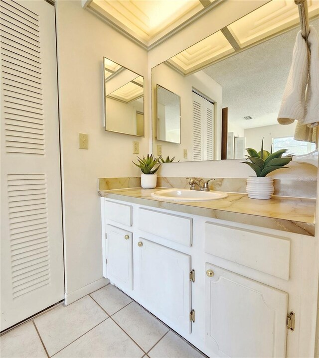 bathroom with a textured ceiling, a closet, tile patterned flooring, and vanity