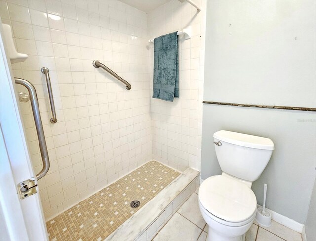 bathroom featuring toilet, tile patterned flooring, baseboards, and a shower stall