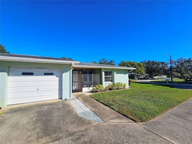 single story home featuring a front lawn, driveway, an attached garage, and stucco siding