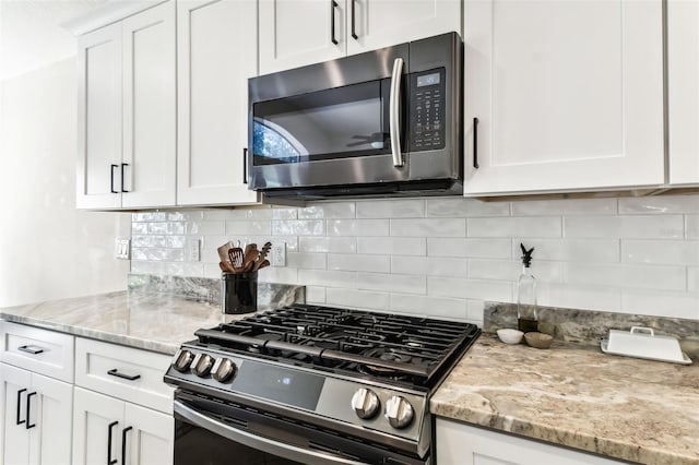 kitchen with white cabinetry, appliances with stainless steel finishes, tasteful backsplash, and light stone countertops