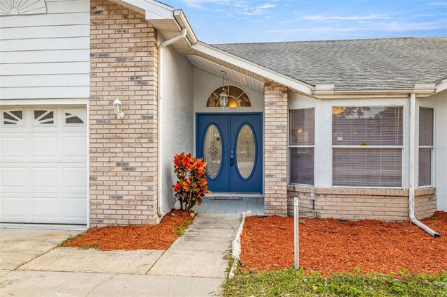8404 Millwood Dr, Hudson, FL 34667 - view of exterior entry featuring brick siding, roof with shingles, and a garage