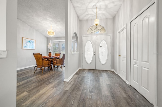 foyer entrance with dark wood-type flooring, a textured ceiling, and a chandelier