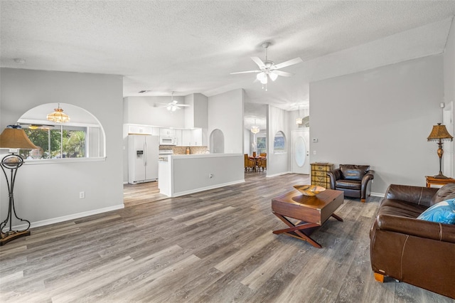 living room with hardwood / wood-style floors, ceiling fan, a textured ceiling, and lofted ceiling