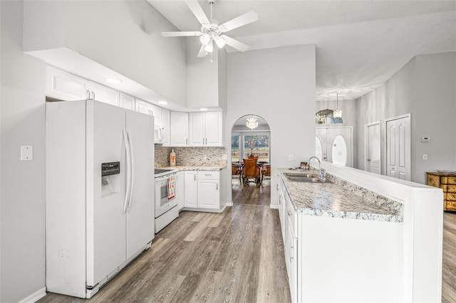 8404 Millwood Dr, Hudson, FL 34667 - kitchen with white appliances, a sink, light wood finished floors, white cabinets, and a peninsula