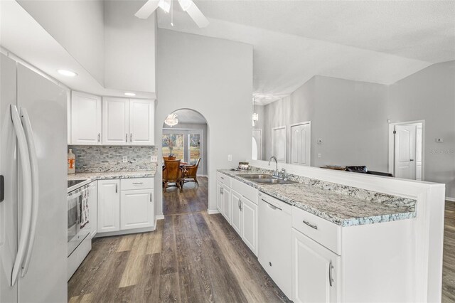 8404 Millwood Dr, Hudson, FL 34667 - kitchen featuring a sink, white appliances, arched walkways, dark wood finished floors, and lofted ceiling