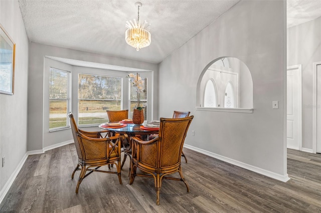 dining space with a textured ceiling, a notable chandelier, and dark hardwood / wood-style floors