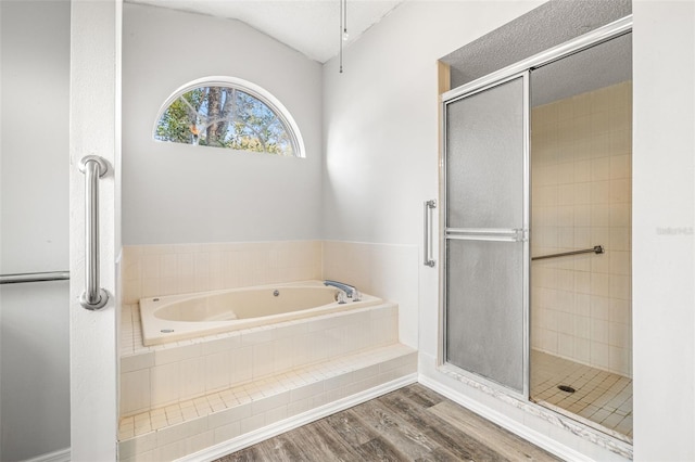 bathroom featuring independent shower and bath, lofted ceiling, hardwood / wood-style floors, and a textured ceiling