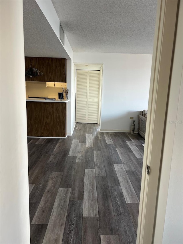 corridor featuring dark wood-type flooring and a textured ceiling