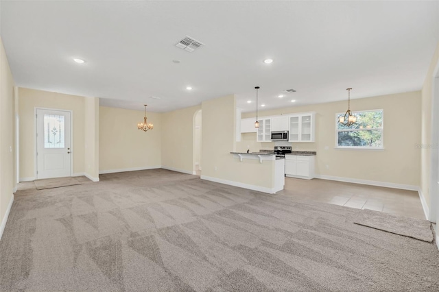 unfurnished living room featuring light carpet and a notable chandelier